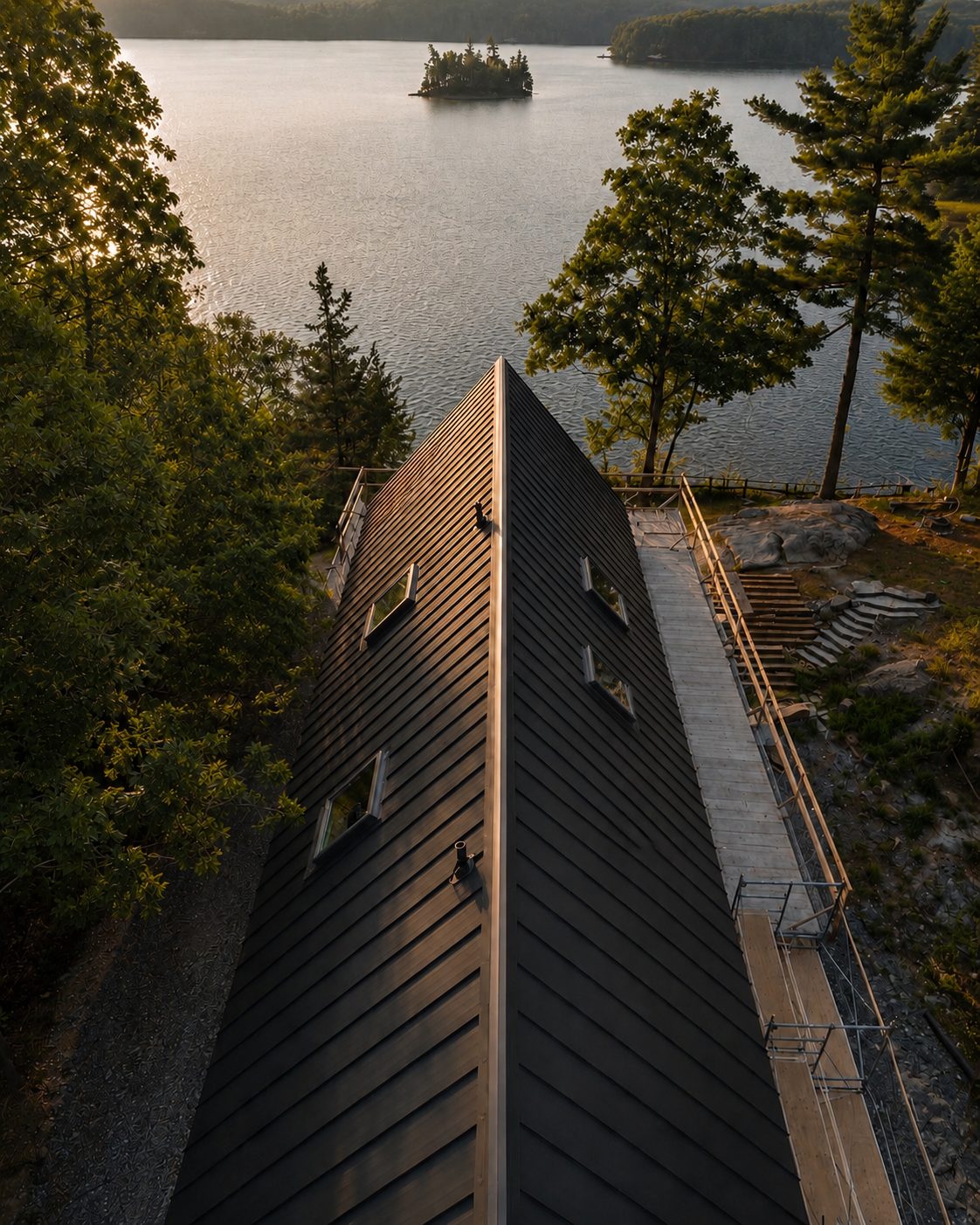 Aerial looking down the finished dark standing-seam ridge toward the lake