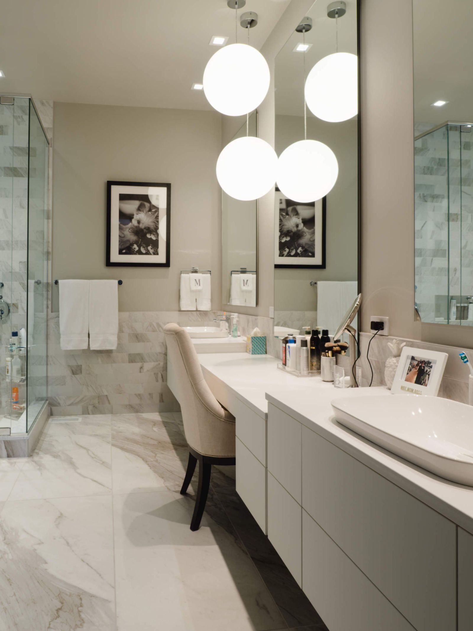 Marble bath with globe pendants and lit double vanity