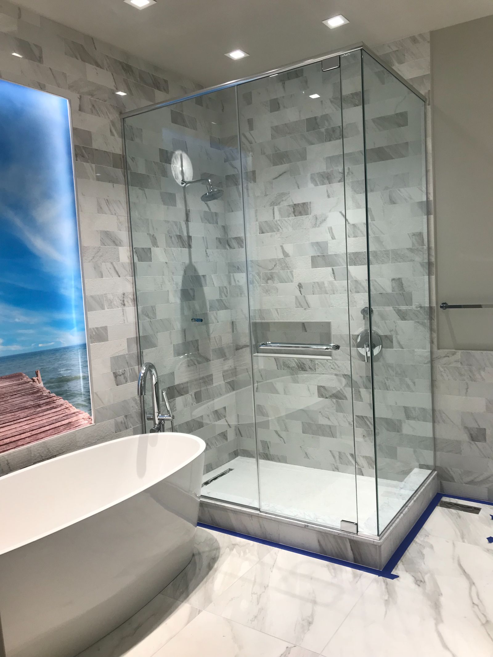 Frameless glass shower in marble tile beside the freestanding tub