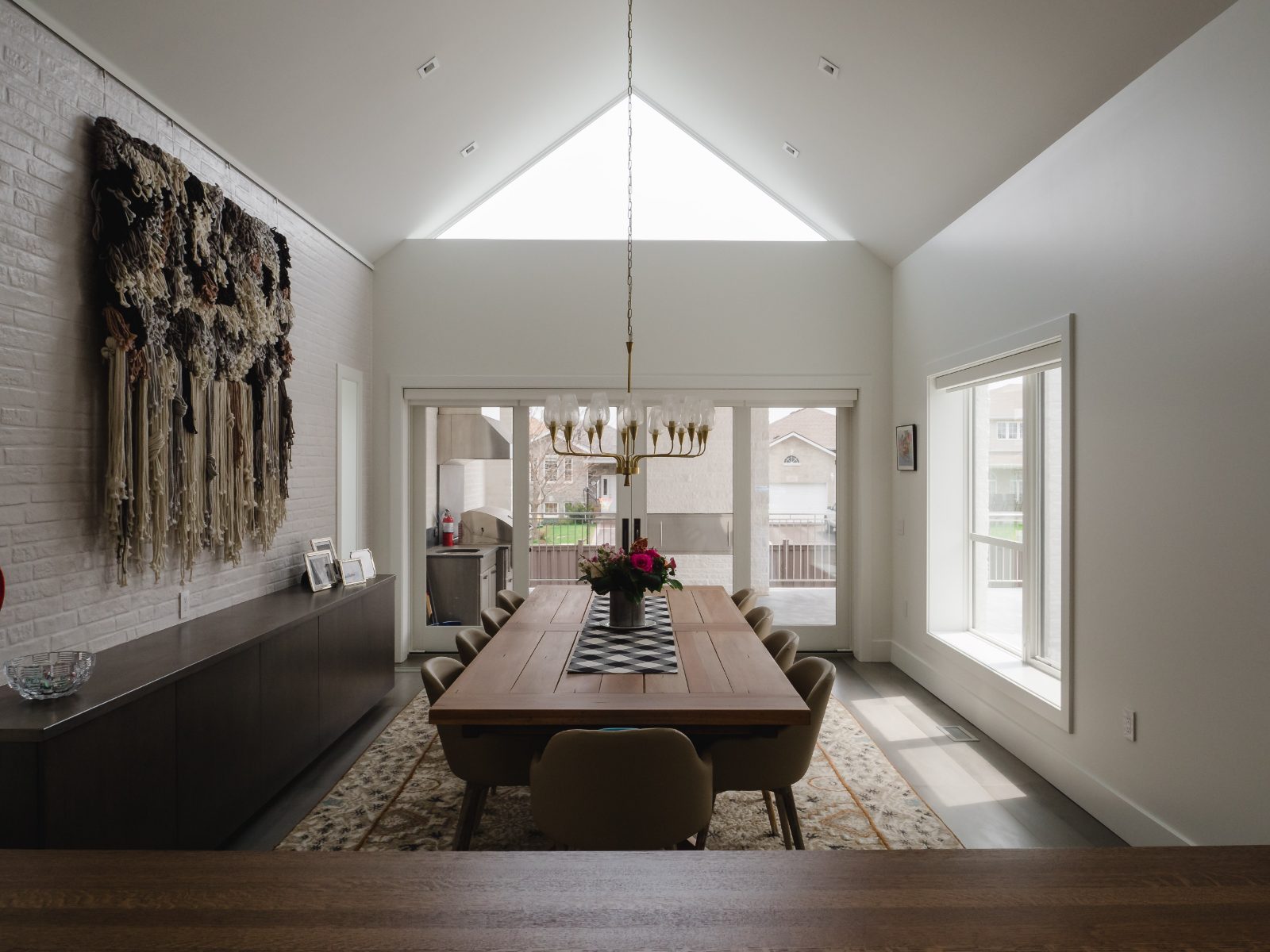 Vaulted dining room with painted brick accent wall and gable window