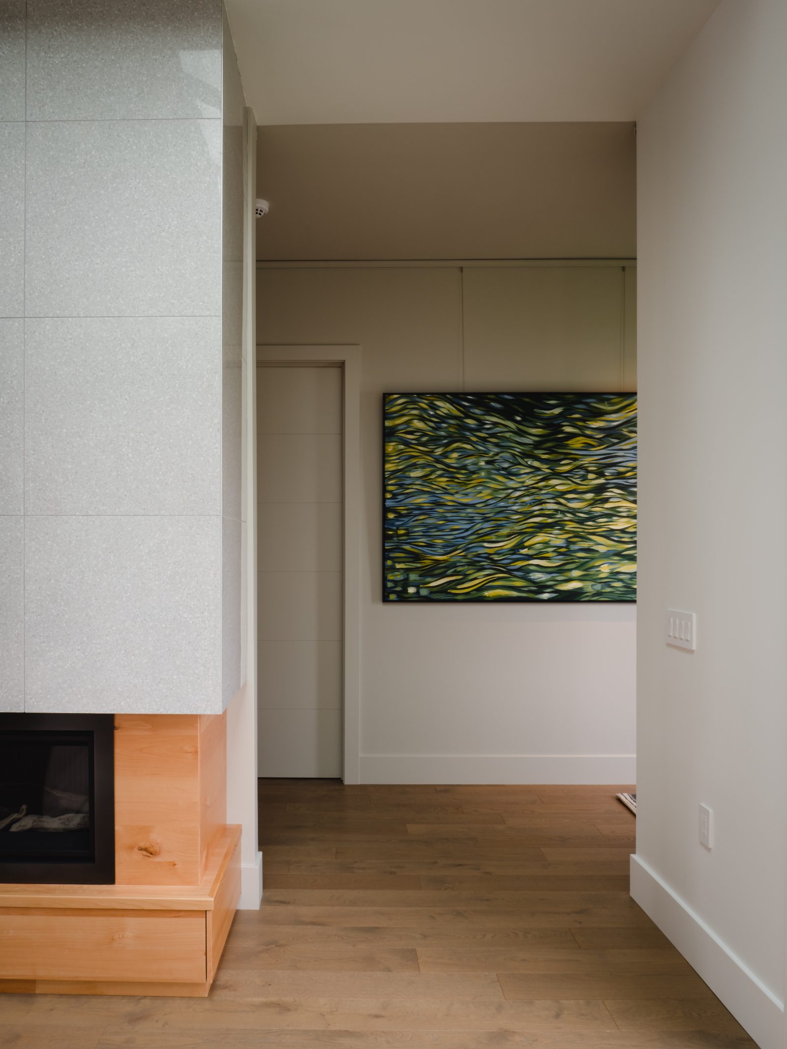 Tiled fireplace surround on maple base, gallery wall beyond