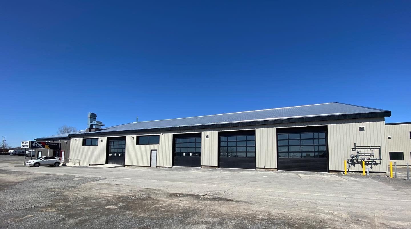 Renovated body shop exterior with new glass bay doors and steel cladding