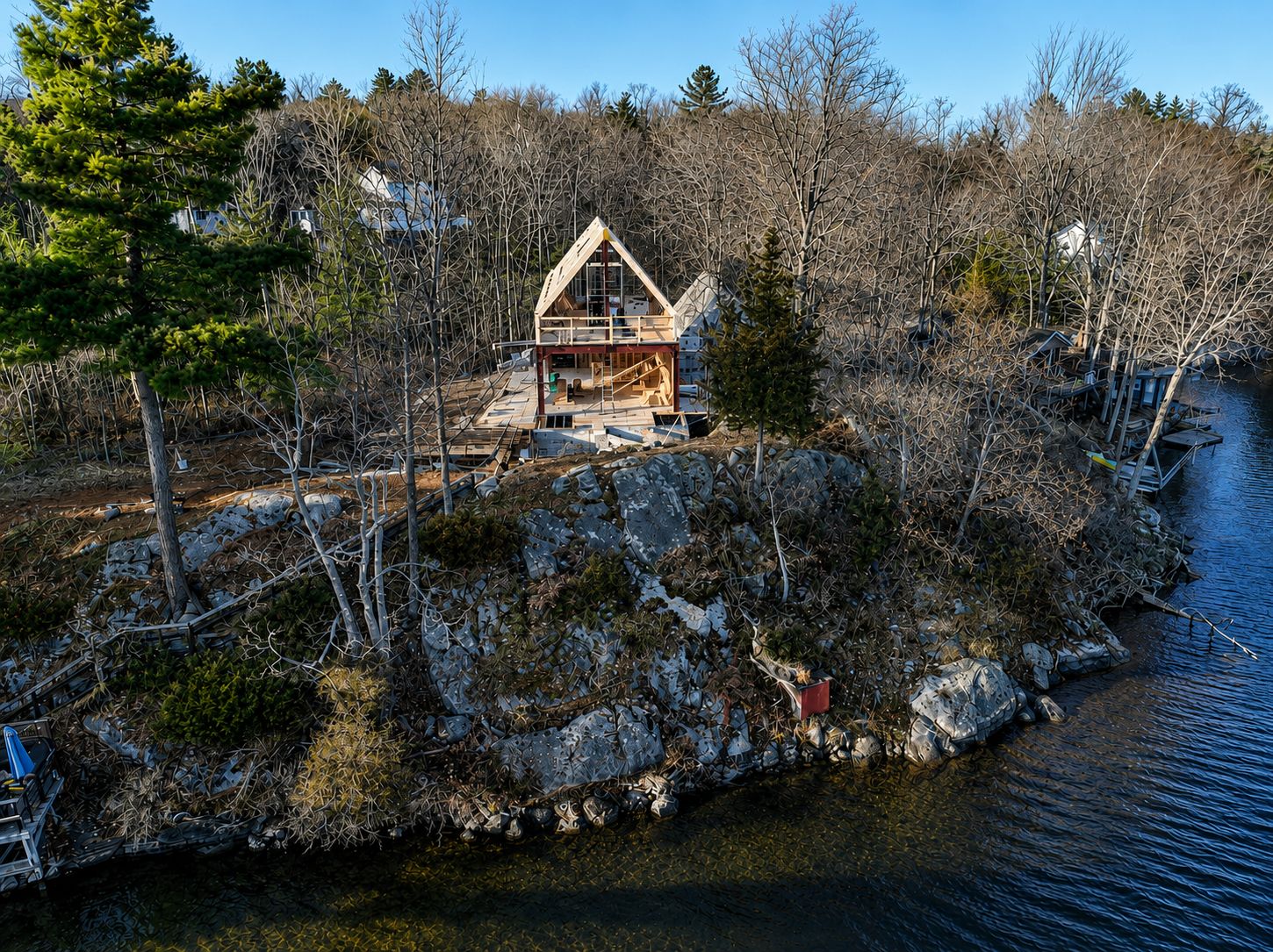 Drone view of the timber A-frame structure rising on a lakefront rock outcrop