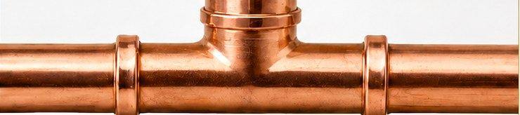 A press-fit copper tee with clean crimped collars at each connection and no heat discolouration