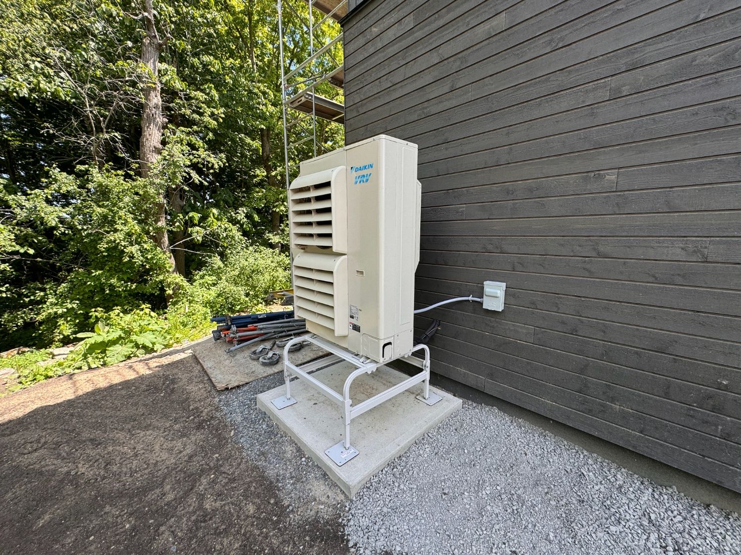 Daikin VRV outdoor heat-pump unit beside charred siding