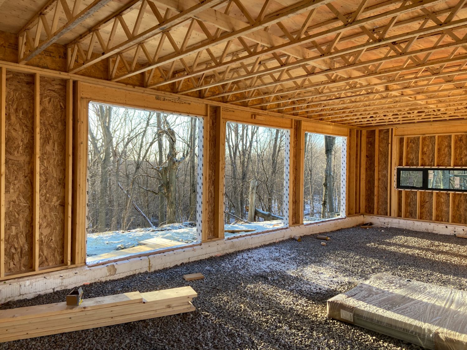 Framed interior with large windows over a clean gravel floor