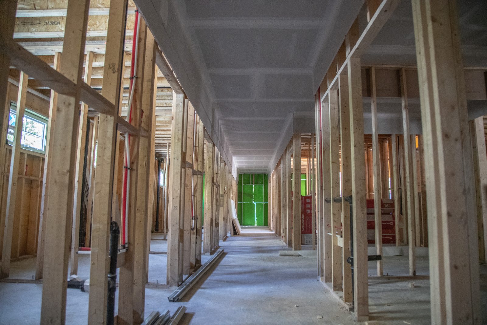 Framed clinic corridor with exam rooms taking shape either side