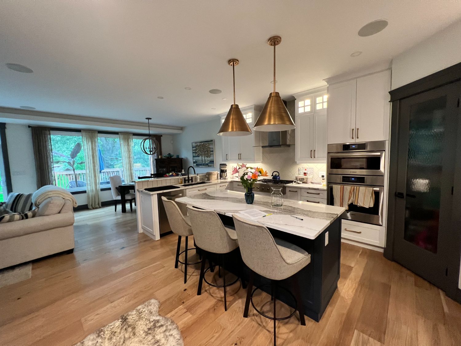 Open-plan white kitchen with navy island and brass cone pendants