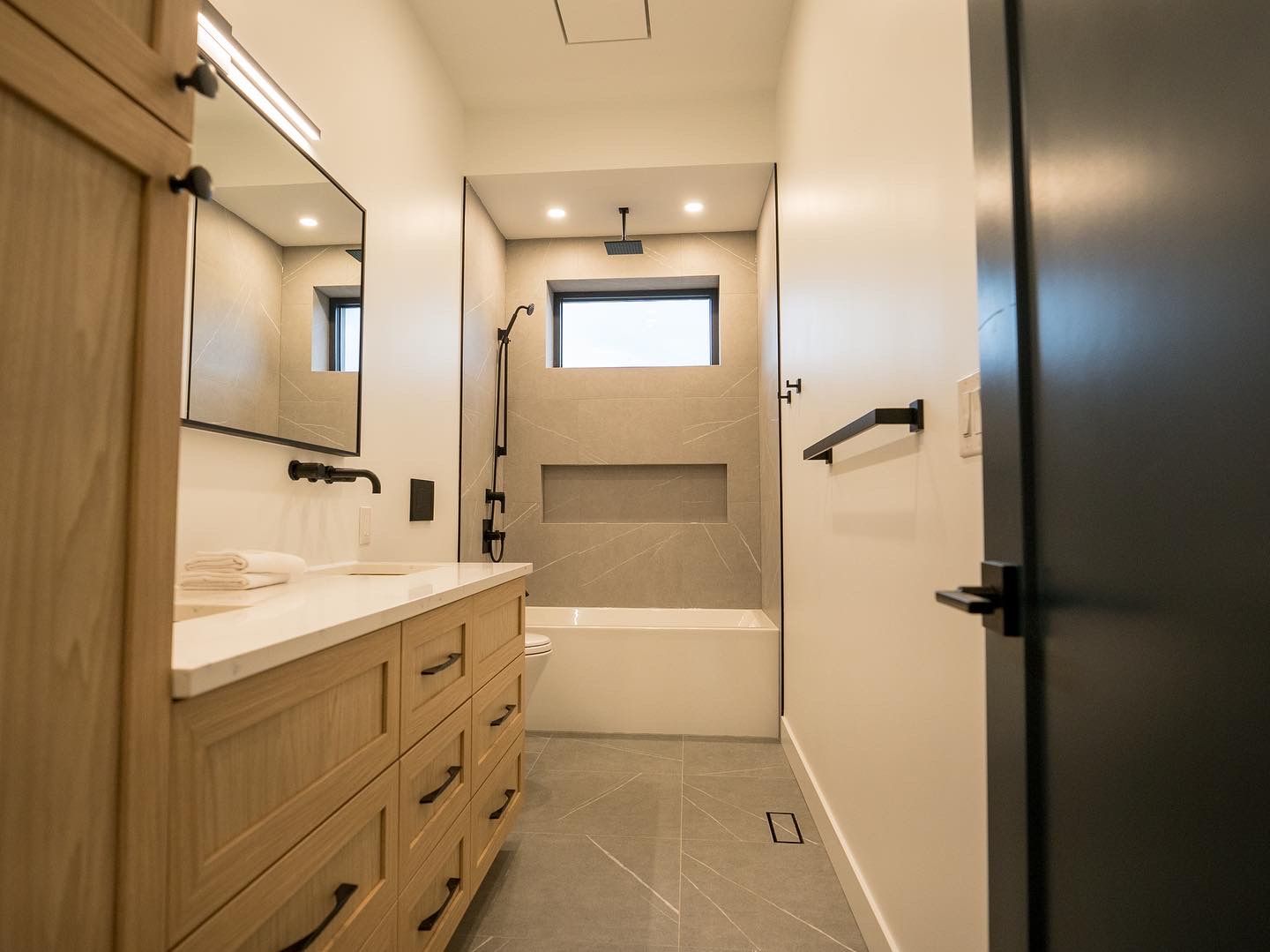 Bath with white-oak double vanity matching the home's millwork