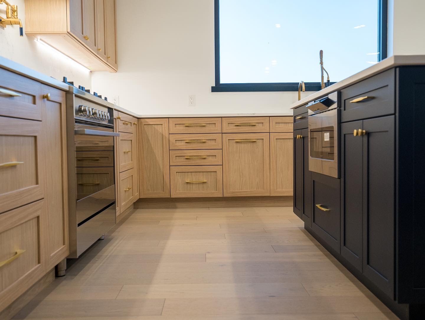 White-oak kitchen with navy island and brass hardware