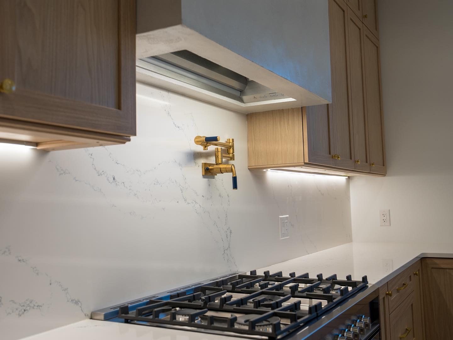 Plaster hood over the range with brass pot filler and quartz backsplash
