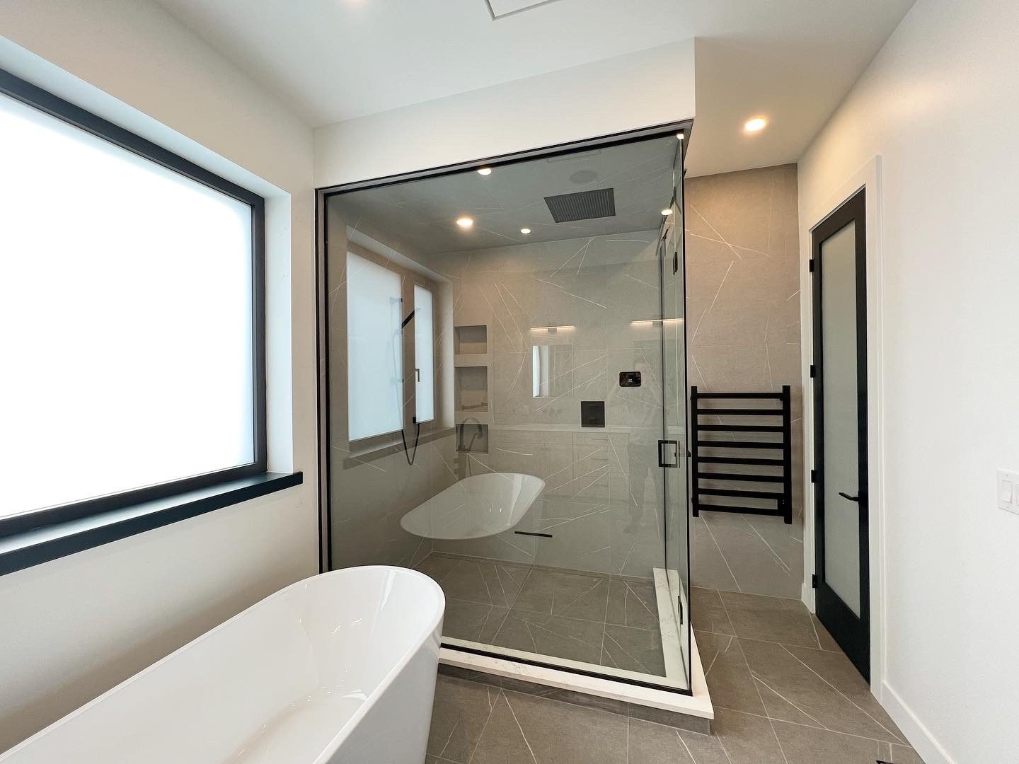 Glassed-in steam shower with a soaker tub inside and freestanding tub beside it