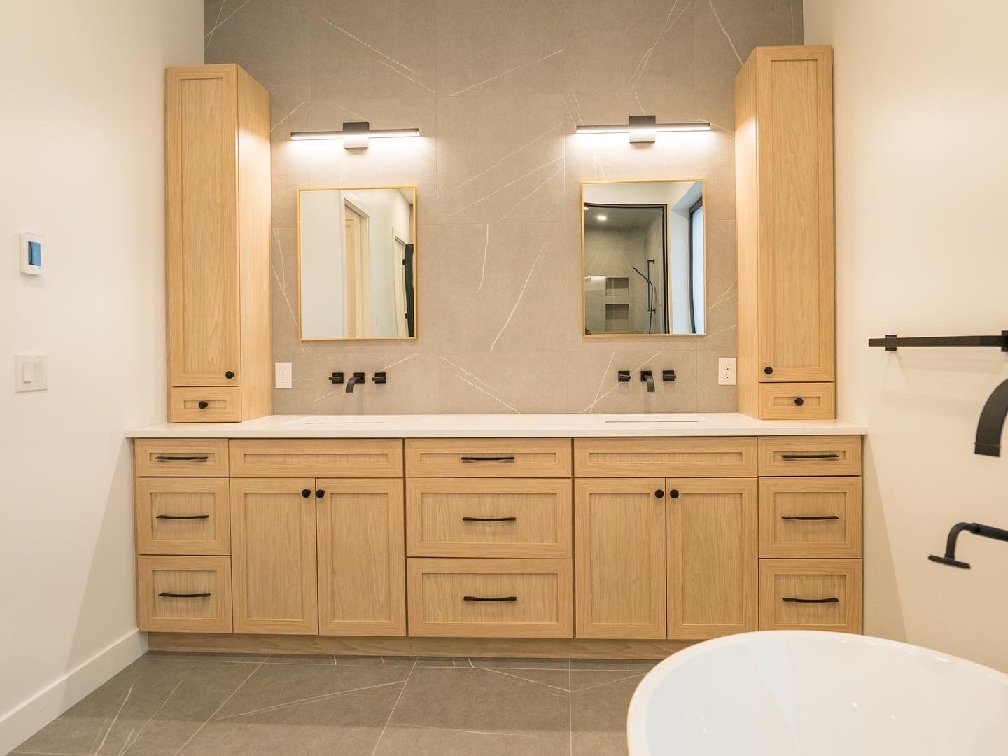 Primary bath with white-oak double vanity, twin mirrors and black fittings