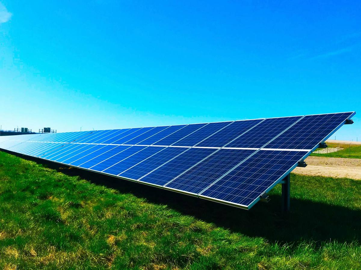 A long ground-mounted solar array on open prairie under a clear sky