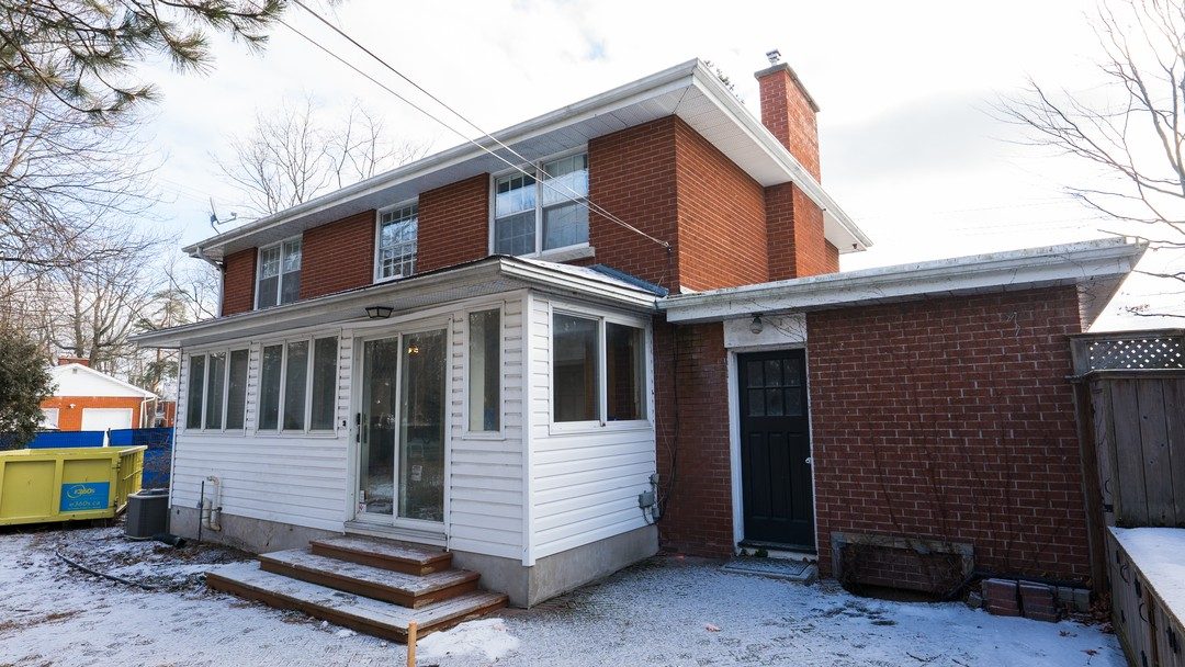 Original brick house with an aging sunroom before construction
