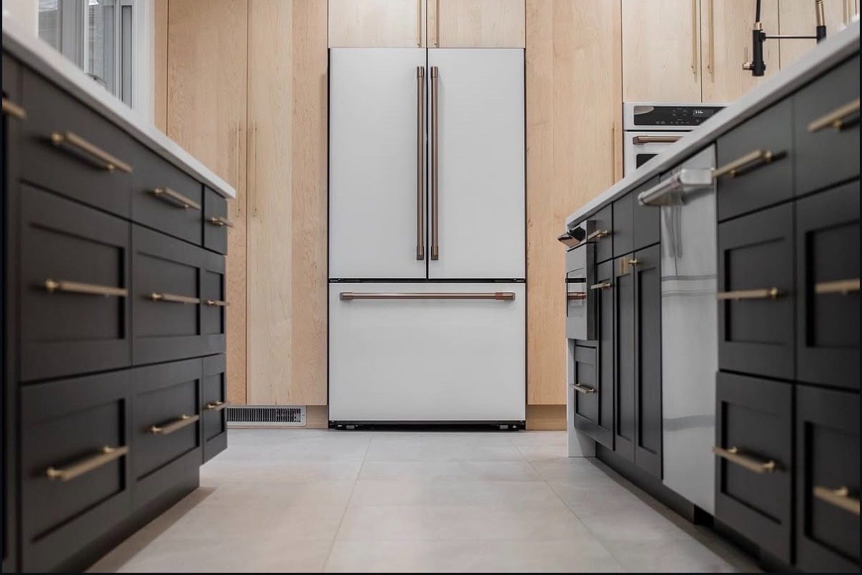 Galley view between black cabinets to a white French-door fridge set into maple
