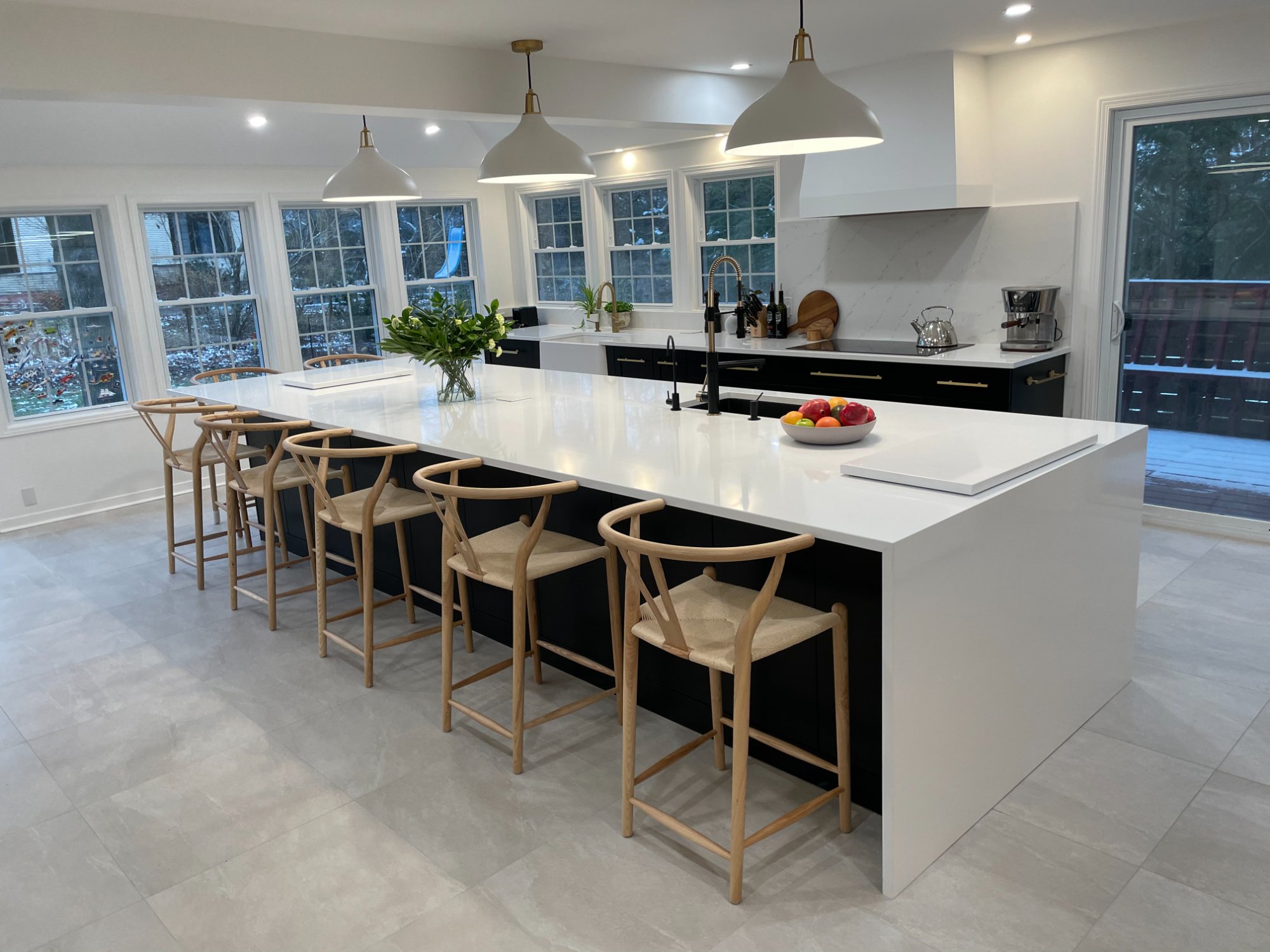 White kitchen with long island under a wall of windows