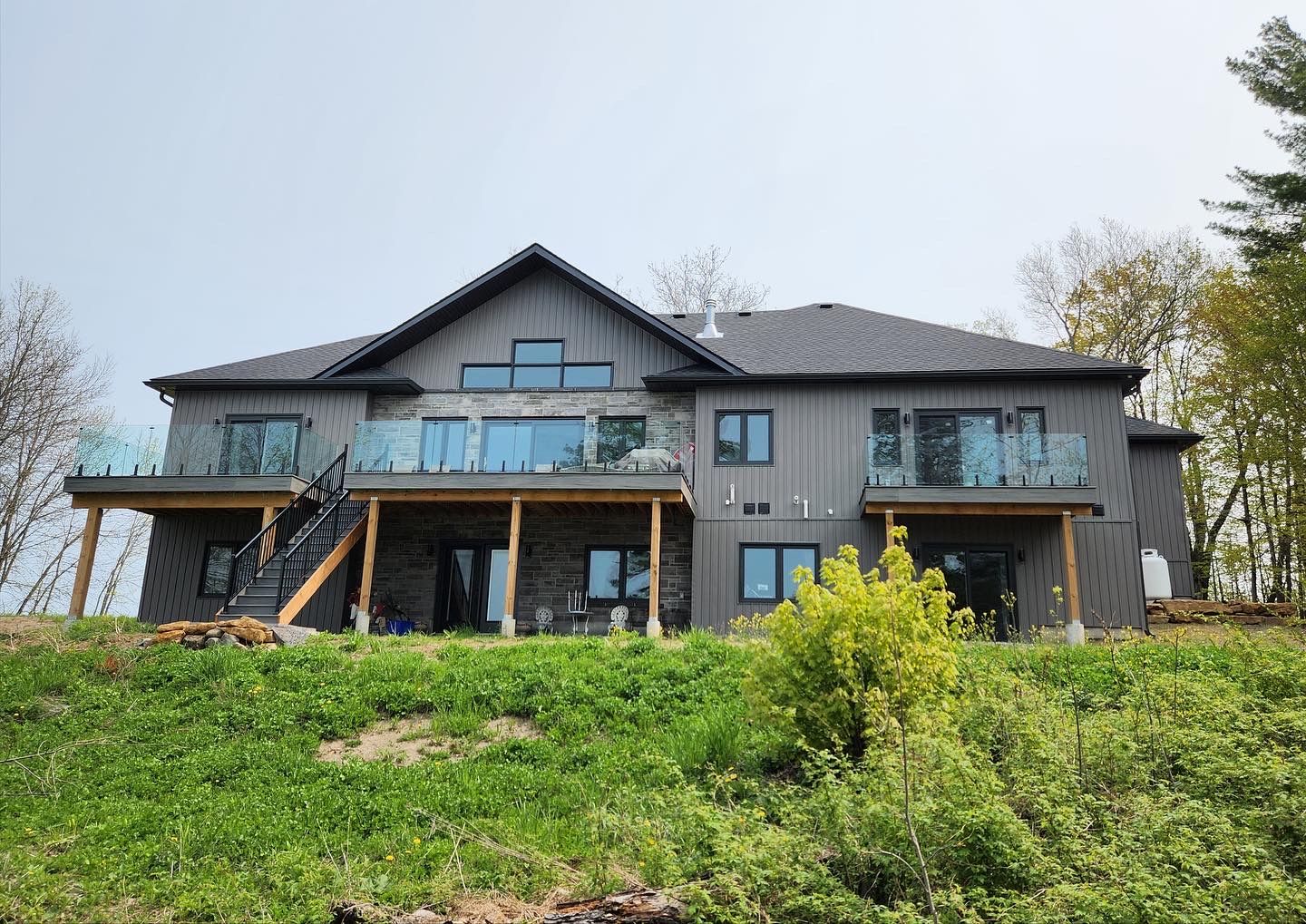Finished lakefront rear elevation with glass-railed deck and stone base
