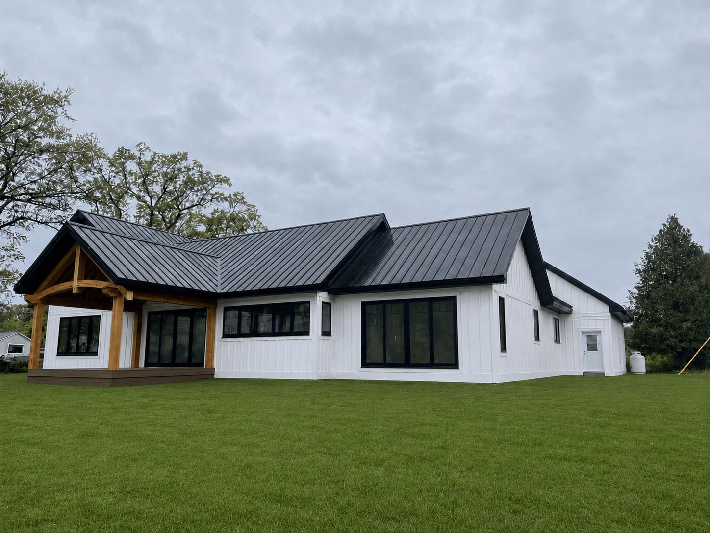 Completed white board-and-batten farmhouse with black standing-seam roof